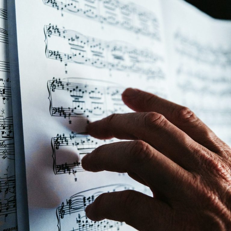 Hand eines Erwachsenen, der Klaviernoten berührt | Klavierunterricht